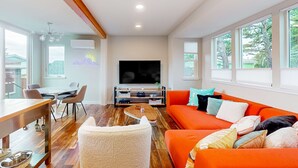 Una sala de estar moderna con un sofá grande color naranja, una mesa de centro de madera y un televisor de pantalla plana.