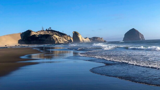 Una playa con grandes formaciones rocosas y cielo despejado.