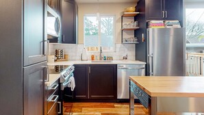 Una cocina moderna con armarios oscuros, electrodomésticos de acero inoxidable y una mesa de comedor de madera.