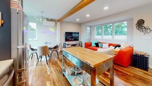 Una sala de estar moderna con una mesa de comedor de madera, un sofá rojo y un televisor.