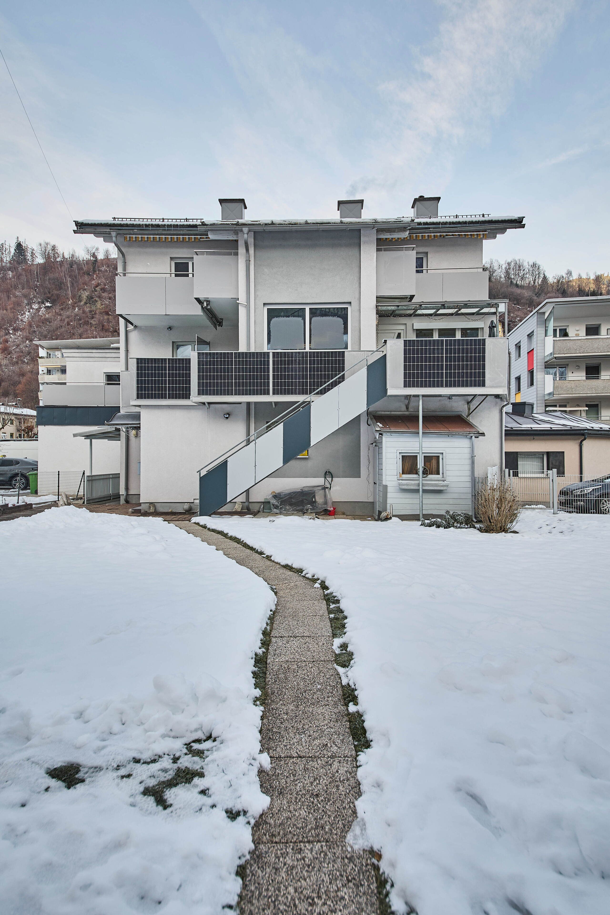 Un bâtiment moderne à deux étages, doté d’un espace extérieur couvert et d’un escalier menant à l’étage supérieur.