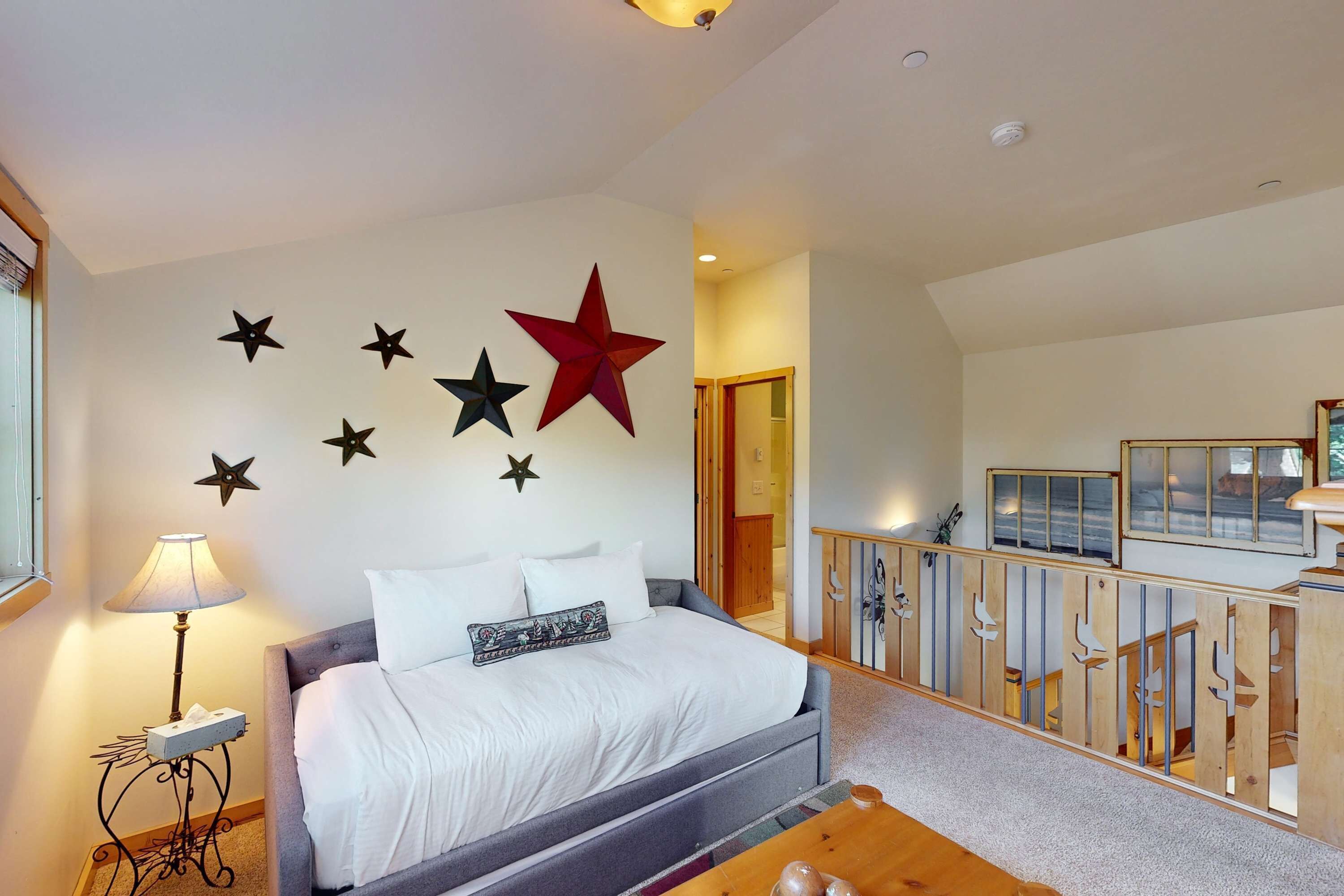 Een slaapkamer met een bed, een nachtkastje, een lamp en een sterren decoratie aan de muur.