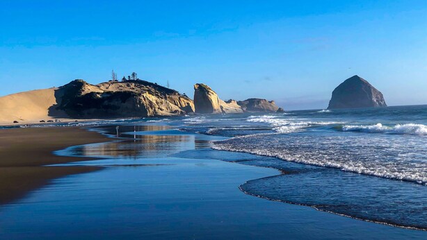 Une plage avec de grandes formations rocheuses et un ciel dégagé.