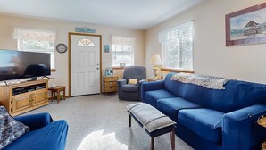 Ein Wohnzimmer mit einem blauen Sofa, einem Fernseher und einem Holzkabinett.