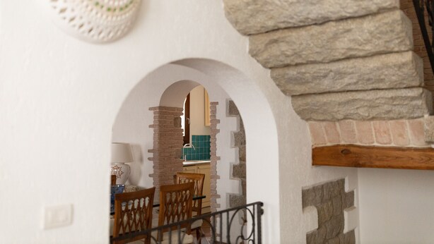 A staircase with stone steps and a wooden handrail, leading to a room with a white wall and an arched doorway. - Casa al Duomo by Wonderful Italy (Telti)