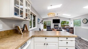 A modern kitchen with white cabinets, a wooden countertop, and a built-in glass cabinet. - Home with gas fireplace washer dryer and 2 outdoor spaces walk to beach (Tierra Del Mar)
