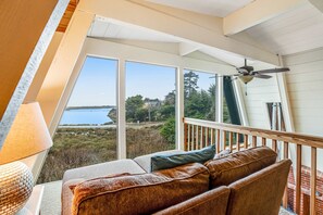 Ein gemütlicher Balkon mit Blick auf einen See und Bäume, ein Deckenventilator und eine Lampe.