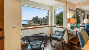 Una habitación acogedora con sillas de mimbre, una mesa con un florero y vistas al exterior.