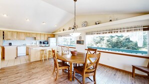 A spacious kitchen with wooden cabinets, a central island, and a dining area with a wooden table and chairs. - Family Friendly Coastal Home with Free WiFi Washer Dryer and Easy Beach Access (Cape Meares)