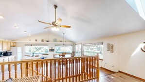 A spacious living area with a wooden floor, a ceiling fan, and a balcony with a railing. - Family Friendly Coastal Home with Free WiFi Washer Dryer and Easy Beach Access (Cape Meares)