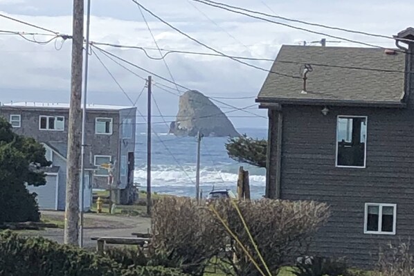 Een huis aan de kust met uitzicht op de oceaan en een opvallende rotsformatie.