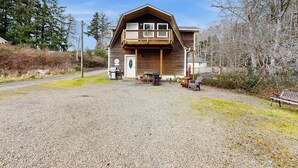 Eine Holzhütte mit Balkon, Kiesweg und Bank.