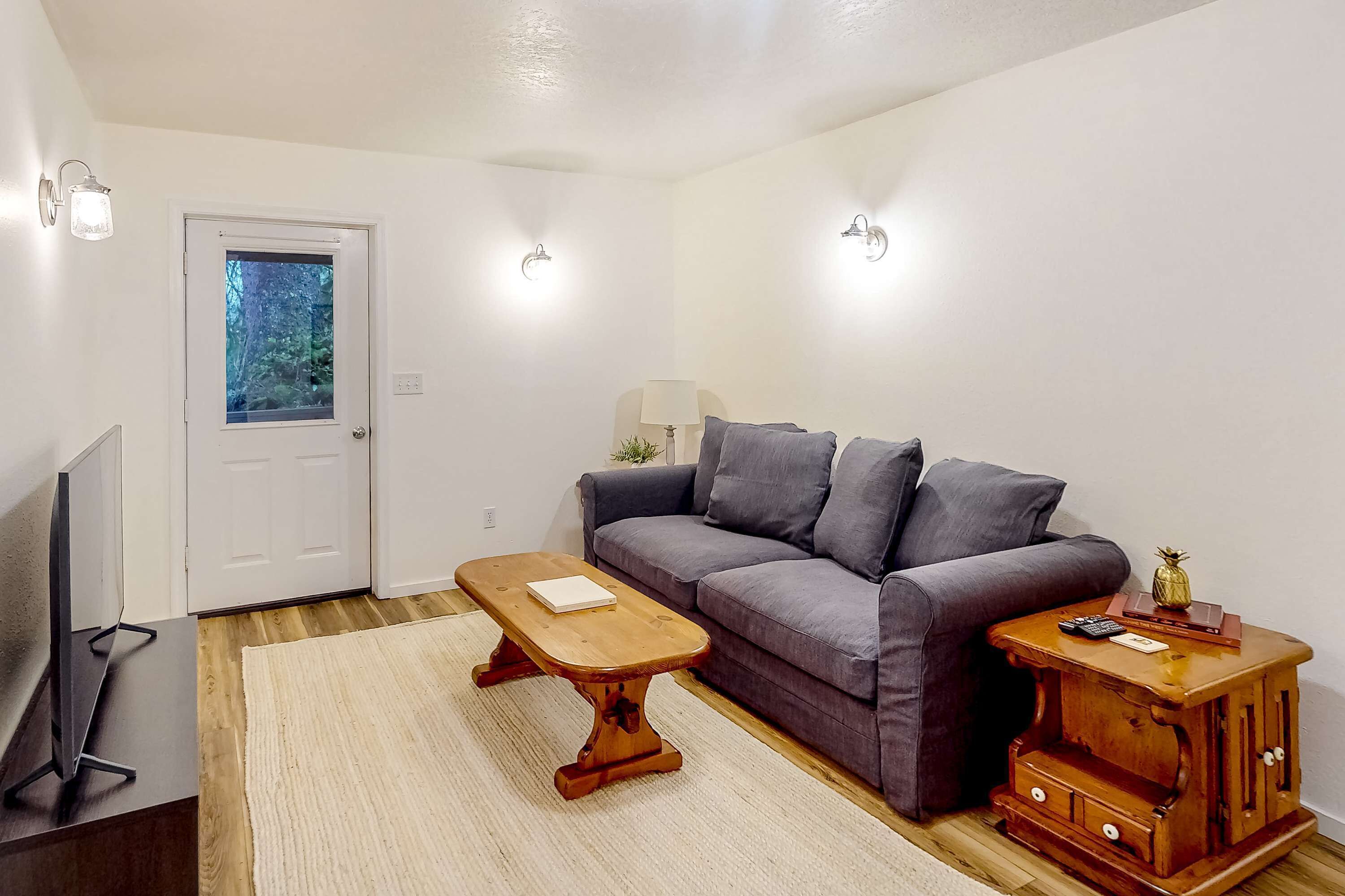 A living room with a sofa, a wooden coffee table, a side table with a lamp, and a television.