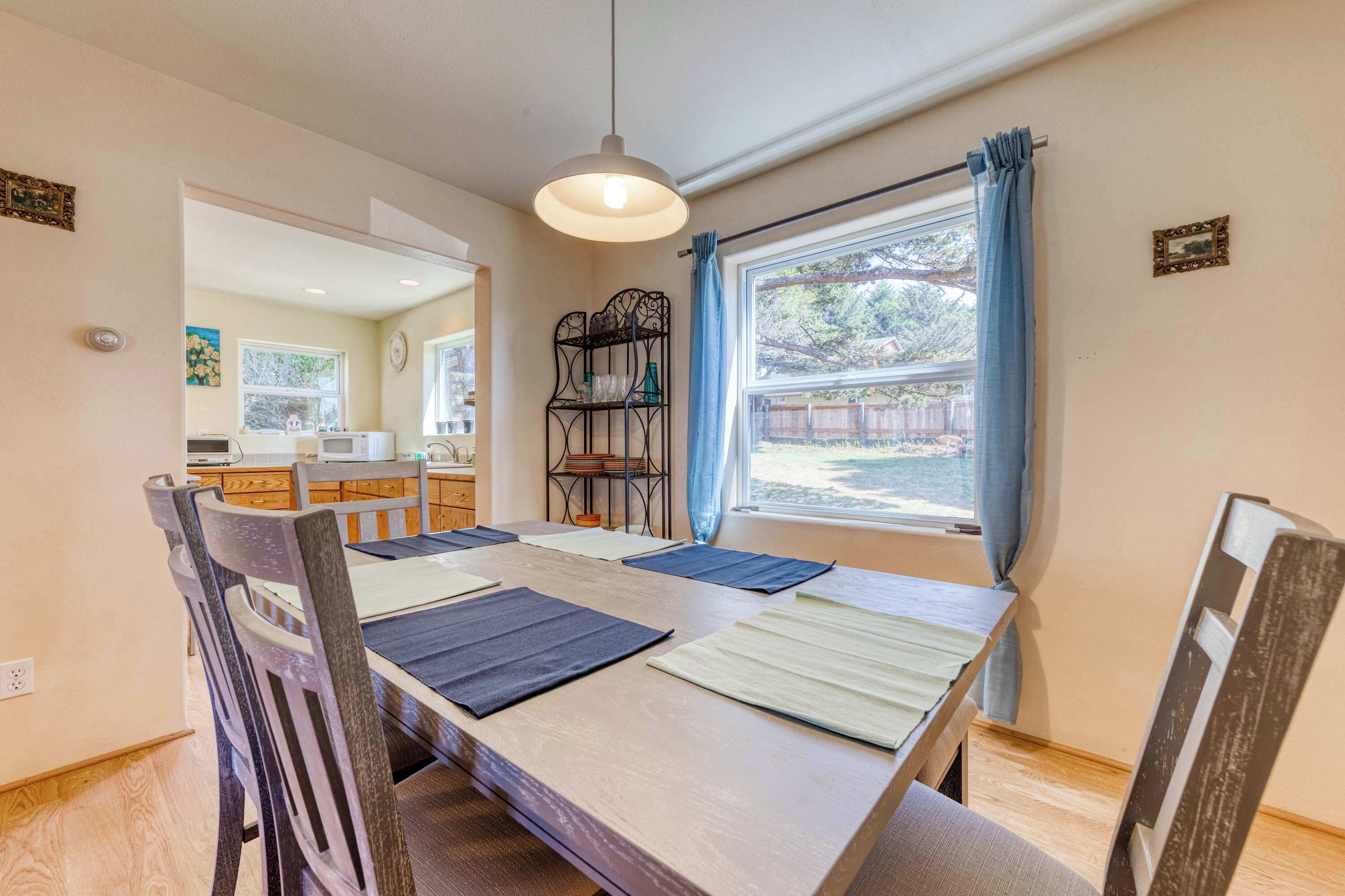 Un coin repas avec une table et des chaises en bois, un luminaire suspendu et une fenêtre avec des rideaux.