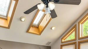 Un dormitorio con cama, tragaluz, ventilador de techo y vistas al exterior.