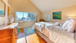 Ein Schlafzimmer mit einem großen Bett, einer Holzkommode, einem Fenster mit Ausblick und einem Bild an der Wand.