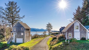 Ein Küstenhaus mit Kiesauffahrt, Garage und Blick auf das Meer und die Berge.