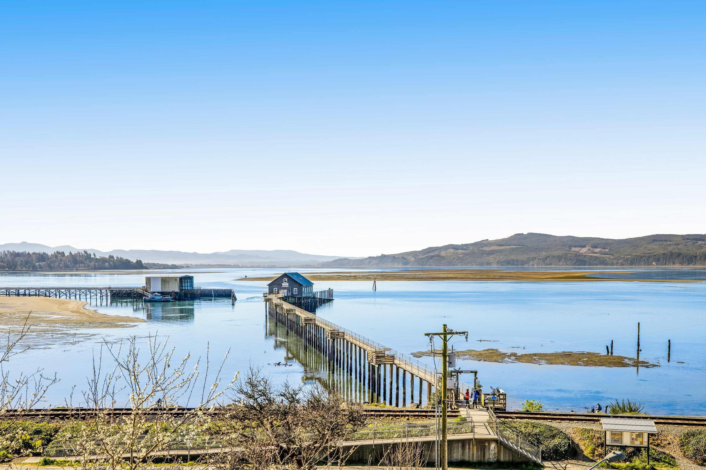 A pier extending into a calm lake with a small house at the end.