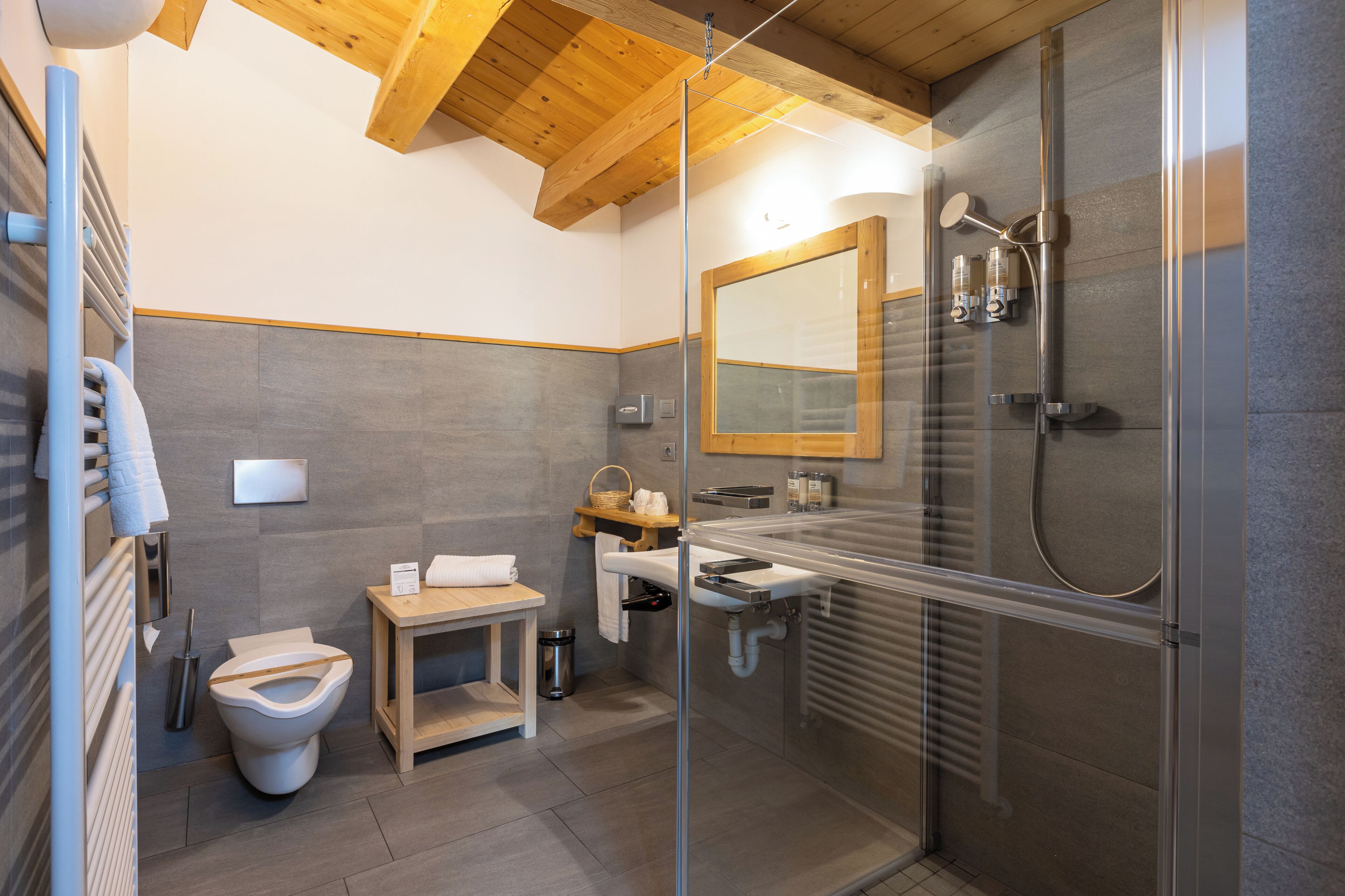 A modern bathroom with a glass-enclosed shower, a wooden vanity, and a toilet.