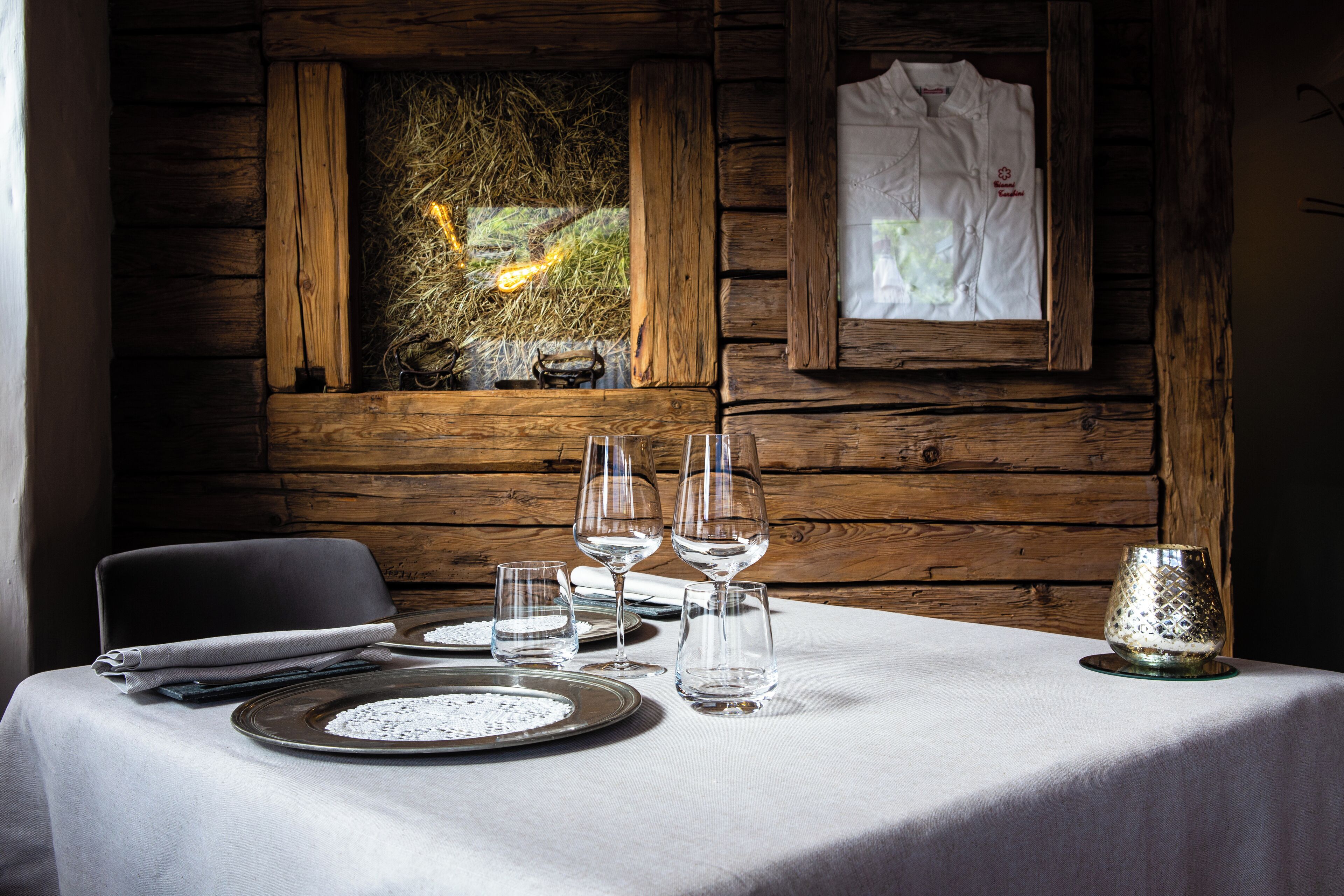 A dining table set with plates, glasses, and cutlery, a candle, and a framed picture on the wall.