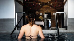 A woman in a swimming pool with a wooden ceiling and string lights. - La Fiorida Agri Relais (Mantello)