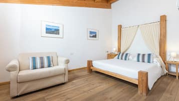 Een slaapkamer met een houten bed, een bank en twee ingelijste foto’s aan de muur.