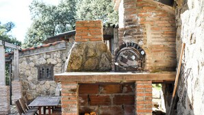 A stone building with a brick oven and a wooden table and chairs.