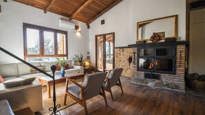 A spacious living room with a fireplace, wooden flooring, and a staircase leading to an upper level.