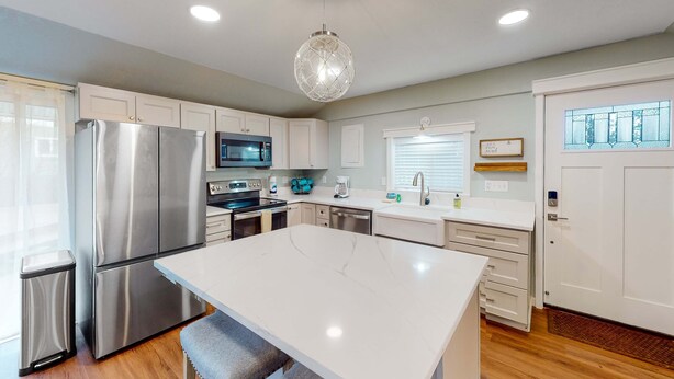 A modern kitchen with stainless steel appliances, a marble island, and white cabinetry.