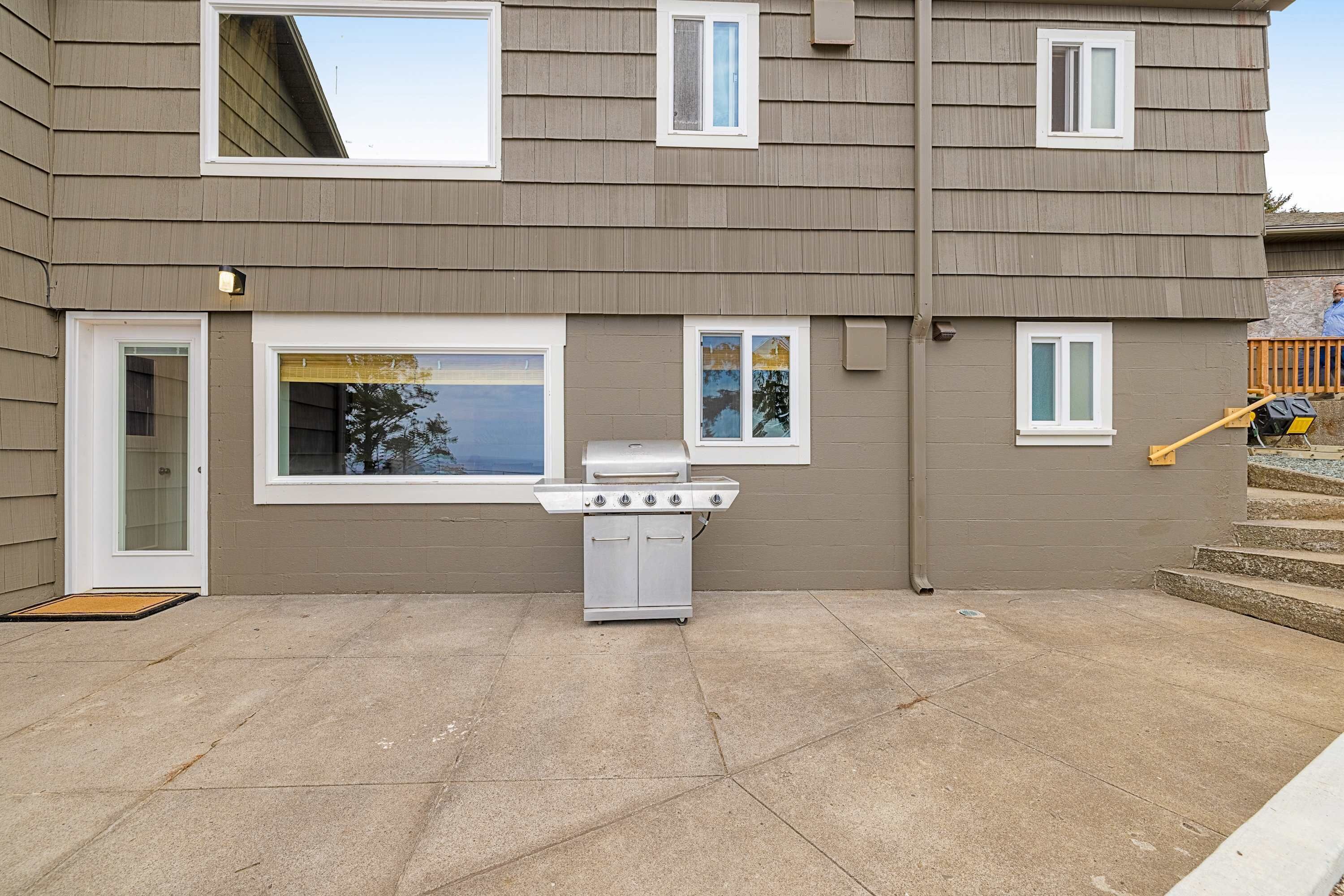 Une maison à deux étages dotée d’un patio comprenant un barbecue au gaz.