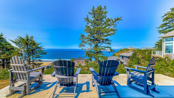Una terraza con sillas Adirondack con vistas a la costa.