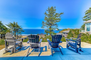 A deck with Adirondack chairs overlooking a coastal view.