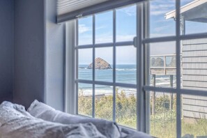 A bedroom with a large window overlooking a rocky island and the ocean. - Incredible Ocean Views Free WiFi Great Location (Oceanside)