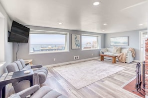 A spacious room with a large window, a flat-screen TV mounted on the wall, a sofa, a coffee table, and a fireplace. - Incredible Ocean Views Free WiFi Great Location (Oceanside)