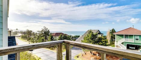 A balcony with a view of a residential area, including houses and a body of water.