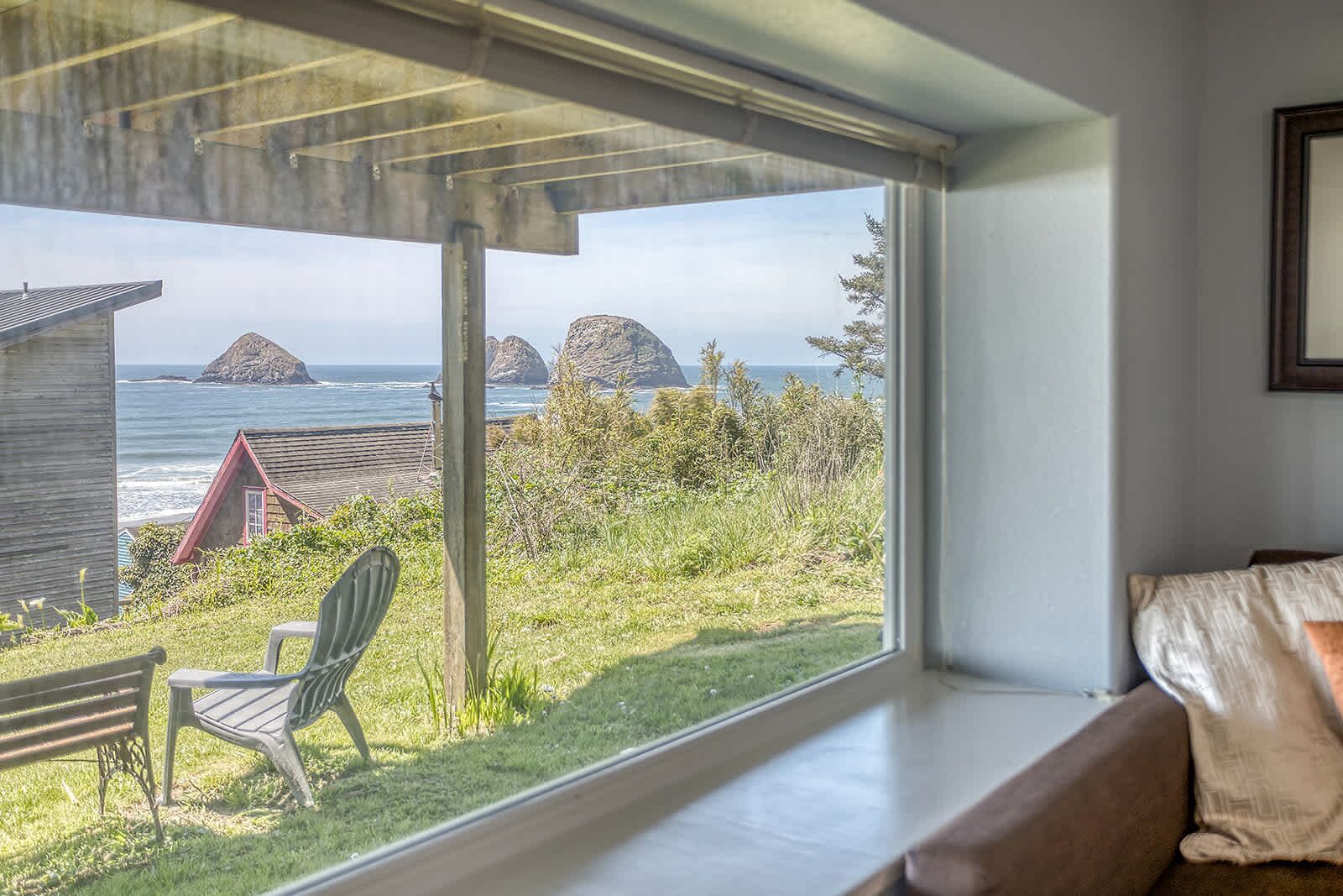 Habitación con un amplio ventanal con vistas a un área verde y al océano.
