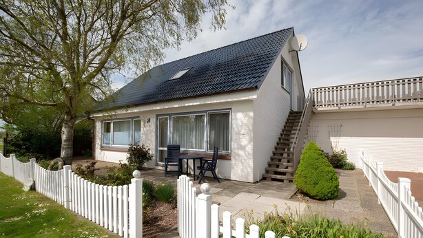 A house with a covered patio, a staircase, and a white picket fence. - Wattenläuper Holiday Apartment (Pellworm)