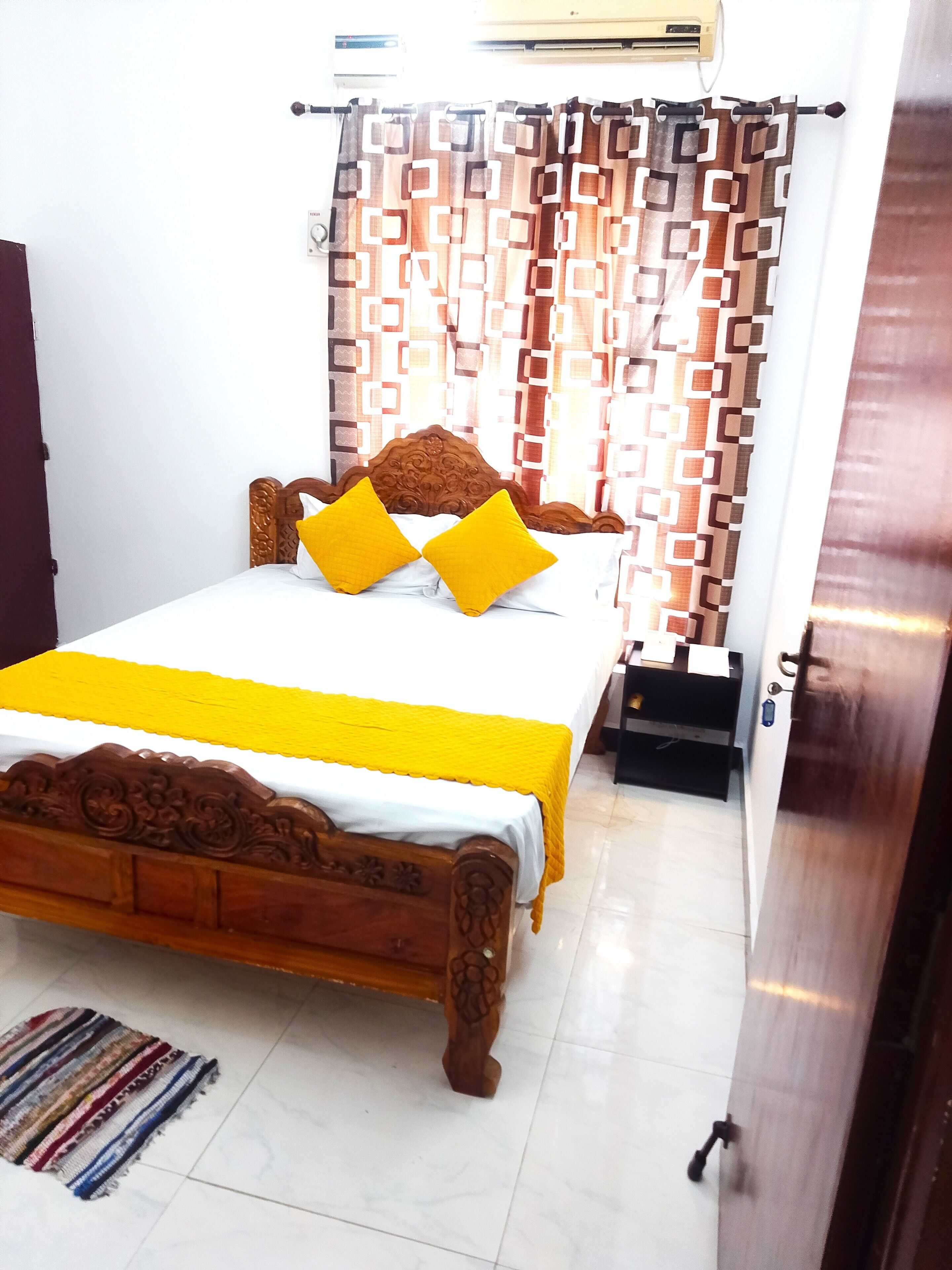 Una cama bien hecha con un cabecero de madera, una colcha amarilla y dos almohadas amarillas.