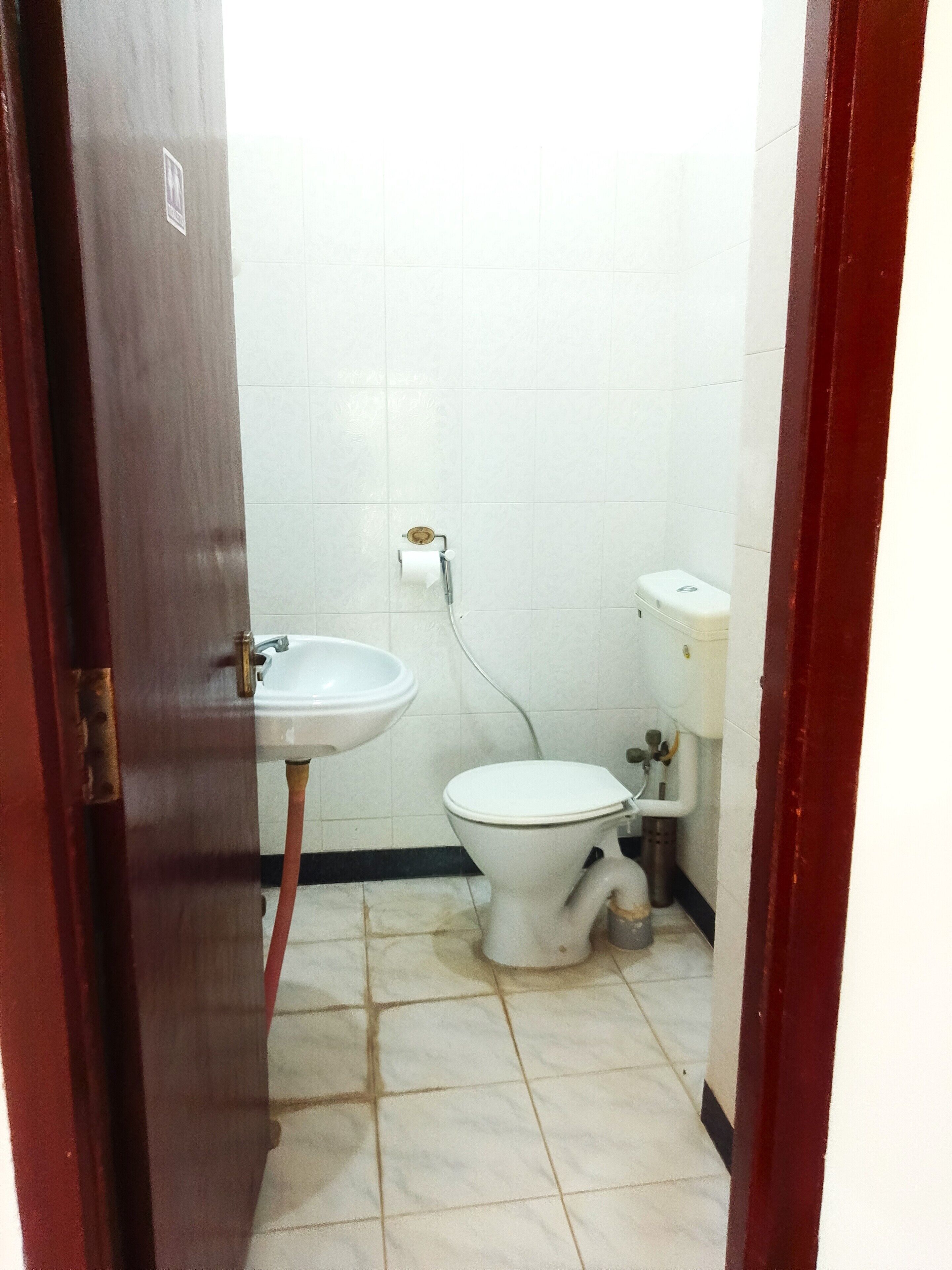 A small bathroom with a toilet, sink, and white tiled walls.