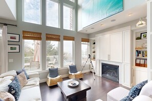 A spacious living room with a fireplace, large windows, and a high ceiling. - Gorgeous Home with Ocean Views Beach Access and Private Hot Tub (Oceanside)