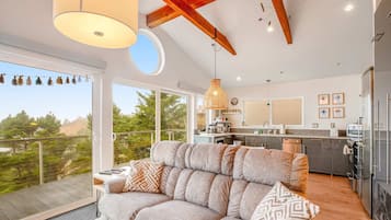 A modern living room with a sofa, a dining area, and a kitchen.