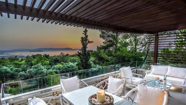 Una terraza con mesa y sillas, con vistas a un paisaje que incluye agua y colinas.