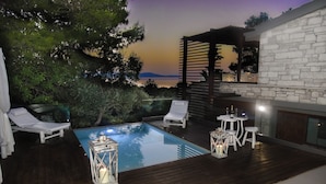 Un área de piscina privada con sillones reclinables, una mesita y un farol.