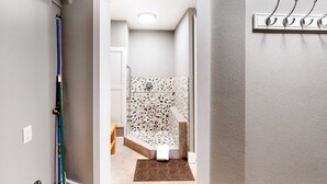 Une salle de bain avec une douche, un porte-serviettes et une porte donnant sur une autre pièce.