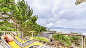 Une terrasse en bois avec deux chaises longues jaunes et une balustrade blanche.