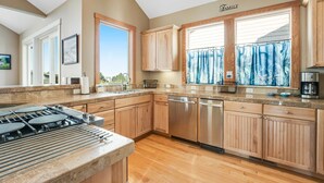 Una cocina moderna con armarios de madera, una estufa integrada y un amplio ventanal con cortinas.