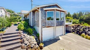 Eingeschossiges Haus mit Garage, umgeben von einer Steinmauer und einer Steintreppe, die zur Haustür führt.