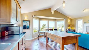 Eine moderne Küche mit Holztisch, Einbauküchenschränken und einem großen Fenster mit Blick auf eine schöne Landschaft.