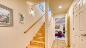 A hallway with wooden stairs, a door, and a table with a purple tablecloth. - Large Sunny Duplex with Ocean Views and Nearby Beach Access Dogs OK (Rockaway Beach)