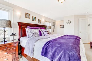 Une chambre à coucher avec un grand lit, une commode, une lampe et des œuvres d’art murales.